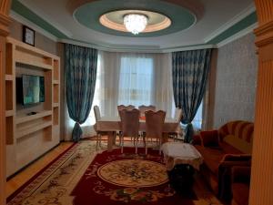 ein Wohnzimmer mit einem Tisch, Stühlen und einem TV in der Unterkunft Villa ELO in Kebele in Qəbələ