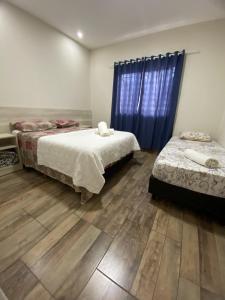 1 dormitorio con 2 camas y cortina azul en Taroba Apart en Puerto Iguazú