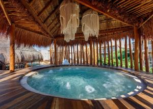 a swimming pool in a bamboo house with a hot tub at Hotel Shibari - Restaurant & Cenote Club in Tulum