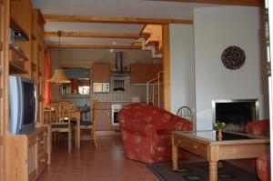 a living room with a red couch and a kitchen at Eule ost und west Ferienhaus im urigen Garten in Zingst