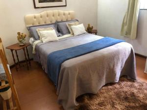 um quarto com uma cama grande e um cobertor azul em Chalé do Vale à 10 min de carro de Itacoatiara em Niterói