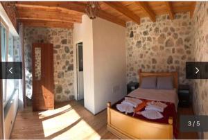 a bedroom with a bed and a stone wall at Thethi Paradise Hotel & Restaurant in Theth