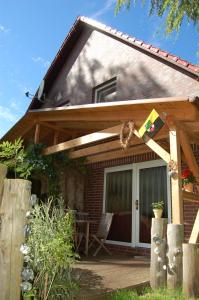ein Haus mit einer Veranda mit einer Flagge darauf in der Unterkunft Ferienhaus im urigen Garten bzw Eulenhaus in Zingst
