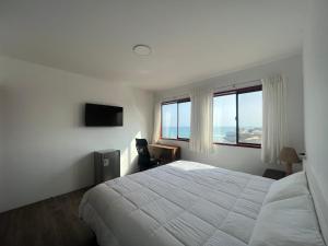 a bedroom with a white bed and a large window at Casablanca del Mar in Punta Hermosa