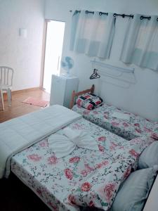 a bedroom with two beds with a floral comforter at Pousada Recanto da Preguiça in Jarinu