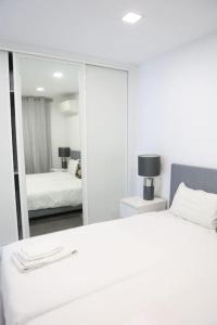 a white bedroom with a mirror and a bed at Lisbon Tagus River - Almada in Almada