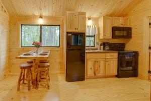 eine Küche mit einem schwarzen Kühlschrank und einem Tisch in der Unterkunft Tranquil Middlebury Center Cabin with Mountain Views 