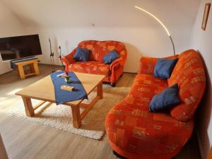 ein Wohnzimmer mit einem orangenen Sofa und einem Couchtisch in der Unterkunft Hedasis Ferienwohnung3, 500 m zum Möhnesee in Möhnesee