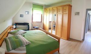 Schlafzimmer mit einem grünen Bett und einem Holzschrank in der Unterkunft Hedasis Ferienwohnung3, 500 m zum Möhnesee in Möhnesee