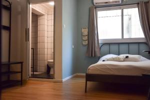 a bedroom with a bed and a window and a bathroom at LevonTLV in Tel Aviv
