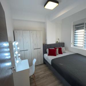 - une chambre avec un lit doté d'oreillers rouges et d'une table dans l'établissement R Lux Apartman Jagodina Akva Park, à Jagodina