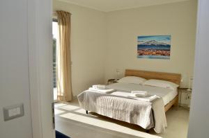 a white bedroom with a bed and a window at Home 13 in San Gregorio di Catania