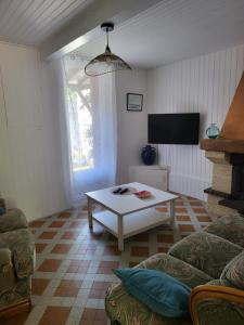 a living room with a coffee table and a tv at La maison rouge paisible maison de pays in Saujon