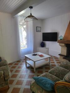 un soggiorno con tavolino e TV di La maison rouge paisible maison de pays a Saujon
