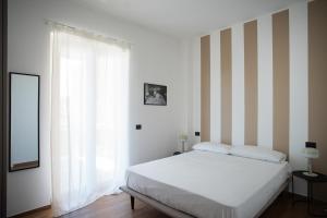 a bedroom with a white bed and a striped wall at Joya Apartment's - Milazzo in Milazzo
