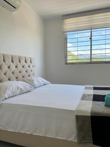 - une chambre avec un grand lit blanc et une fenêtre dans l'établissement Cerca del Paraíso, Río Guatapuri, à Valledupar