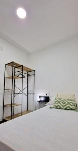 a bedroom with a white bed and a shelf at Loft el Baix - Cullera in Cullera