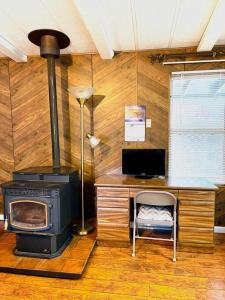 a room with a stove and a desk with a chair at Green Cabin in Midpines in Midpines