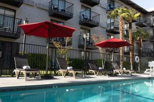 a pool with chairs and umbrellas next to a building at Oxford Suites Lancaster in Lancaster