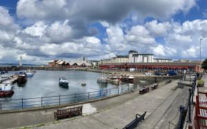 a group of boats docked in a river with buildings at Corinthian Quay Apartment in Edinburgh