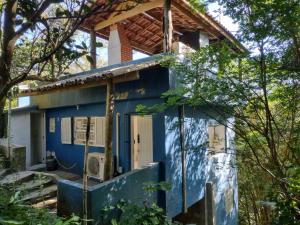 une maison bleue avec une porte dans les bois dans l'établissement O melhor por do sol de Paúba! Casa Aconchegante., à São Sebastião