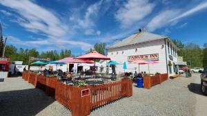 a farmers market with tables and umbrellas in front of a building at The Fairview Inn in Talkeetna