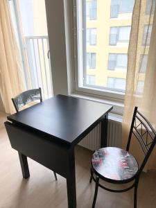 a black table and chairs in a room with a window at PEURANIITTY 3 - Modern easygoing apartment in Espoo