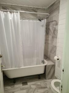 a bathroom with a white shower curtain and a bath tub at The Fairview Inn in Talkeetna