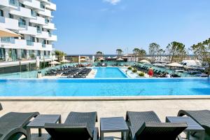 a large swimming pool with chairs and a building at Unique Sea View Infinity Pool & Spa in Mamaia Nord
