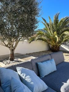 un canapé avec des oreillers assis à côté de deux arbres dans l'établissement Nice house with garden near the sea, à Brem-sur-Mer
