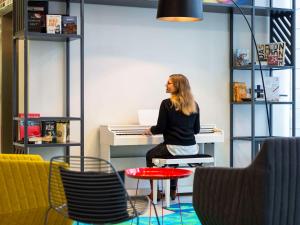 Eine Frau, die an einem Schreibtisch mit Tastatur sitzt. in der Unterkunft Aparthotel Adagio Köln City in Köln