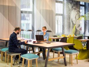 a man and a woman sitting at a table with a laptop at Aparthotel Adagio Köln City in Cologne +33 photos