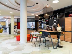 a woman sitting at a table in a lobby at Aparthotel Adagio Köln City in Cologne