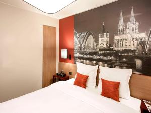 a bedroom with a bed with a painting on the wall at Aparthotel Adagio Köln City in Cologne