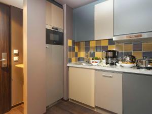 a kitchen with white cabinets and tiles on the wall at Aparthotel Adagio Köln City in Cologne