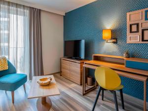 a living room with a television and a table and chairs at Aparthotel Adagio Köln City in Cologne