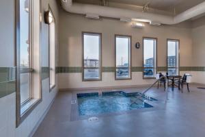 Best Western Plus Moose Jaw في موسجاو: حمام سباحة في غرفة مع نوافذ