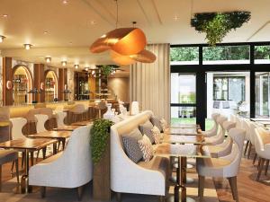 a restaurant with white chairs and tables and windows at Mercure Paris Ouest Saint Germain in Saint-Germain-en-Laye