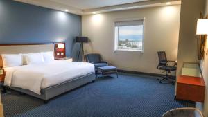 Habitación de hotel con cama, 2 sillas y ventana en Best Western Santorin, en Ciudad Victoria