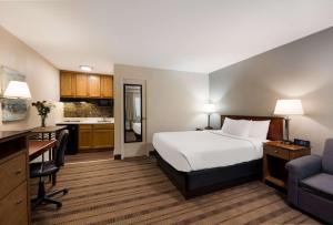 a hotel room with a bed and a desk and a kitchen at SureStay Plus by Best Western Woodbury Inn in Woodbury