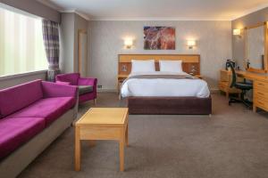 um quarto de hotel com uma cama e um sofá roxo em Best Western Heath Court Hotel em Newmarket