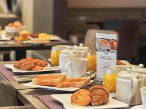 - une table avec des assiettes de viennoiseries et des tasses de jus d'orange dans l'établissement Mercure Paris Saint Cloud Hippodrome, à Saint-Cloud