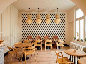 メスにあるMercure Grand Hôtel Metz Centre Cathédraleの木製のテーブルと椅子、壁のあるレストラン