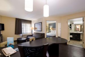 a living room with a table and a room with a bed at Sonesta Simply Suites St Louis Earth City in Earth City