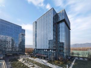 a tall glass office building with two towers at Hilton Garden Inn Beijing Haidian Daoxiang Lake in Beijing