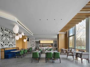 a restaurant with tables and green chairs and a staircase at Hilton Garden Inn Beijing Haidian Daoxiang Lake in Beijing