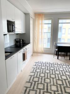 a kitchen with white cabinets and a table at PEURANIITTY 3 - Modern easygoing apartment in Espoo