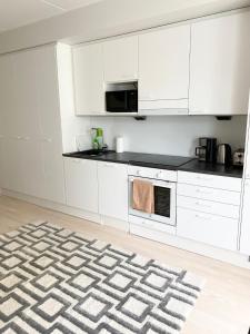 a kitchen with white cabinets and a rug at PEURANIITTY 3 - Modern easygoing apartment in Espoo