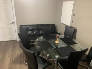 a dining room with a glass table and black leather couch at Lovely apartment house in Grimsby