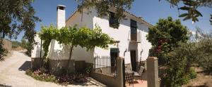 a white house with a bench and a fence at La Laguna in Almedinilla